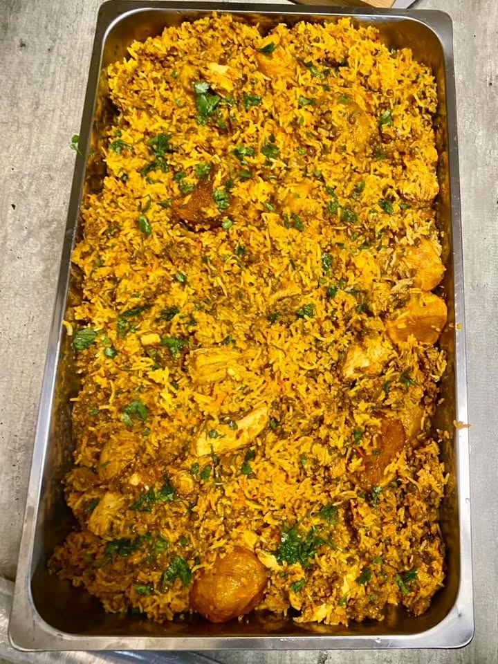 A full tray of chicken biryani topped with fresh coriander